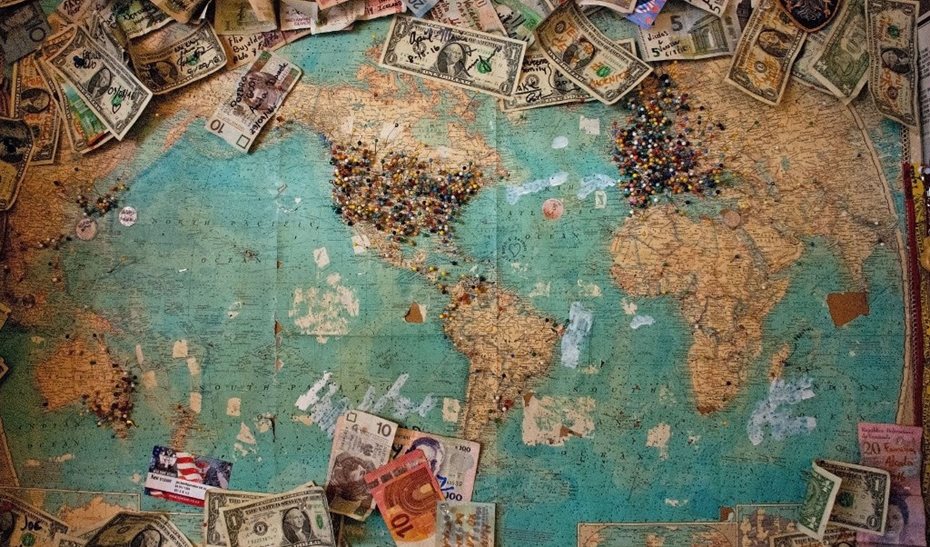 world map with coins and bank notes layed out over it